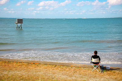 Rear view of man looking at sea against sky