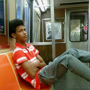 Young man looking away while sitting on seat