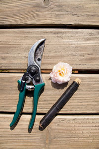 Directly above shot of rose and pruning shears with string on wooden table
