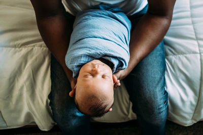 Overhead portrait of sleeping baby in dads arms