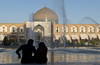 Silhouette people in front of historic building against clear sky