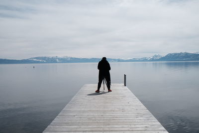 Rear view of man standing on lake against sky