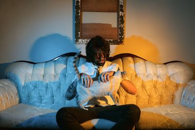 Man holding cat while sitting on sofa at home