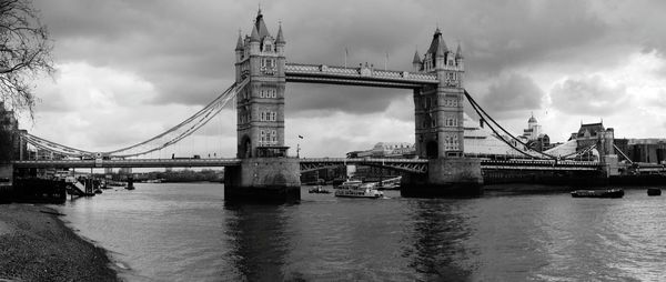 View of suspension bridge over river against cloudy sky