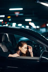 Side view of young woman sitting in car