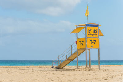 Information sign on beach against sky