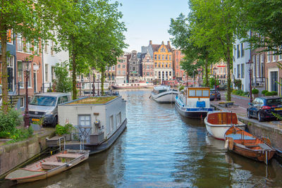 Boats moored in canal amidst buildings in city