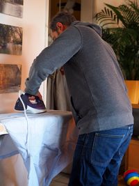 Man ironing clothes on board at home