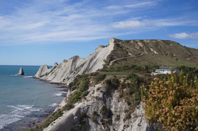 Idyllic shot of cliff by sea against sky