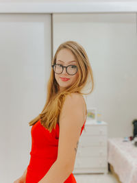 Portrait of young woman standing against wall