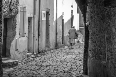 Rear view of man walking on footpath amidst buildings