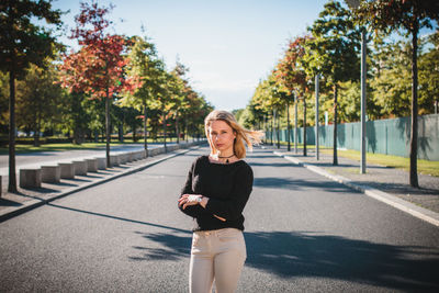 Young woman standing on road against trees