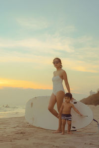 Young woman on beach against sky during sunset