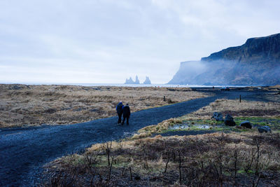 Rear view of men on landscape against sky