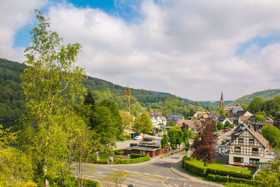 Road amidst trees and buildings against sky