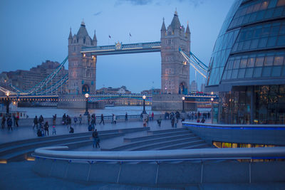 Low angle view of tower bridge over thames river by sidewalk at dusk