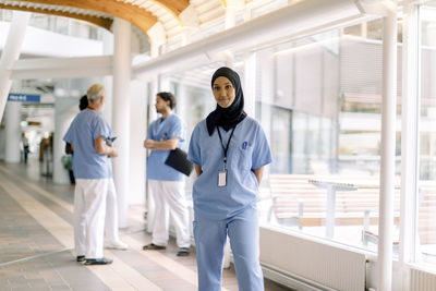 Portrait of female nurse wearing hijab while standing in hospital corridor