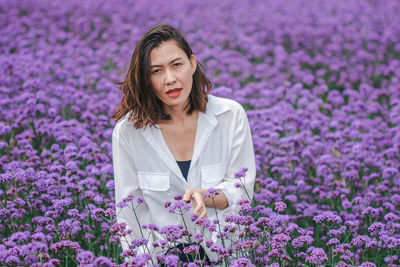 Portrait of beautiful woman standing amidst purple flowering plants
