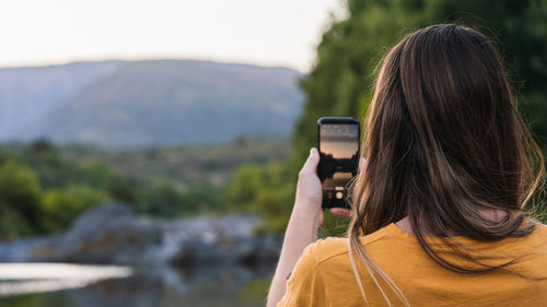 Rear view of woman photographing outdoors