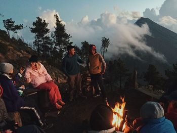 People sitting on bonfire against sky