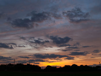 Silhouette trees on field against sky at sunset