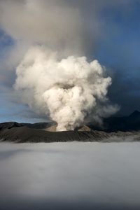 Smoke emitting from volcanic mountain against sky