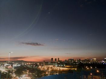 Illuminated cityscape against sky at night