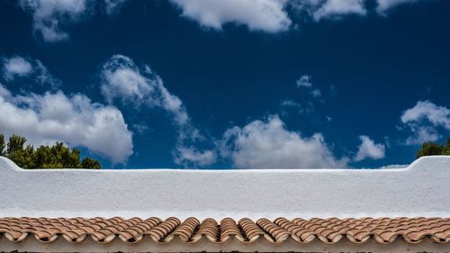 Low angle view of roof against blue sky on sunny day