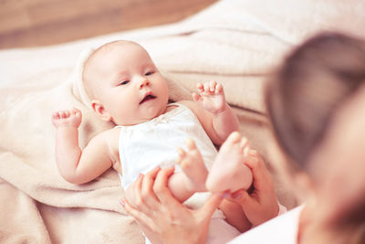 Cute baby girl lying on bed at home