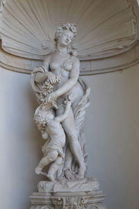 Low angle view of angel statue against white wall
