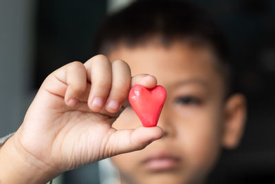 Close-up of boy holding red heart shape