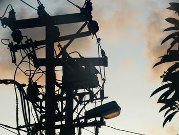 Low angle view of silhouette bird on cable against sky