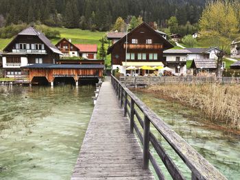 Pier amidst lake leading towards houses