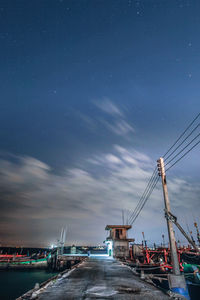 Illuminated pier by sea against sky at night