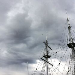 Low angle view of electricity pylon against storm clouds