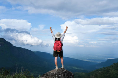 Rear view of man standing on mountain against sky