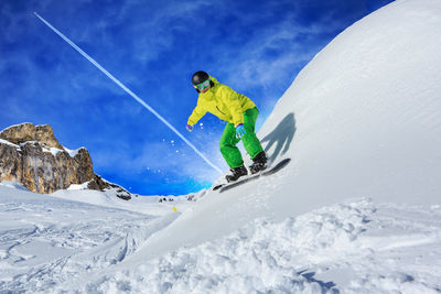Full length of man snowboarding on snowcapped mountain against sky