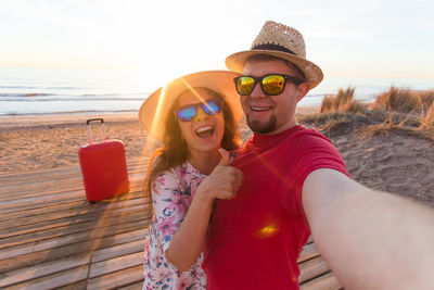 Happy friends enjoying at beach against sky