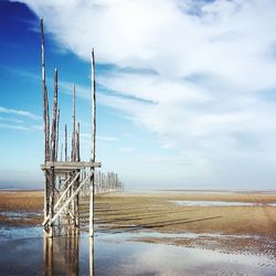 Wooden posts on beach against sky