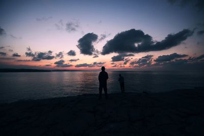 Silhouette man standing on beach against sky during sunset