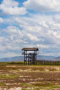 Lifeguard tower on field against sky