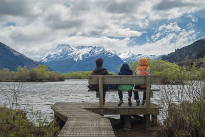 Rear view of people looking at lake against mountain range