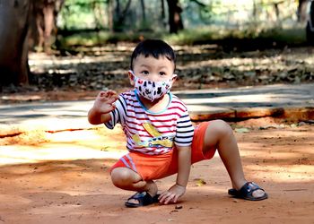 Cute boy crouching on land