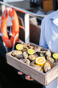 A variety of fresh oysters with lime and lemon in wooden box. fresh seafood. outdoor cafe terrace