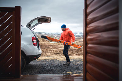 Man loading skis into the trunk of suv in driveway