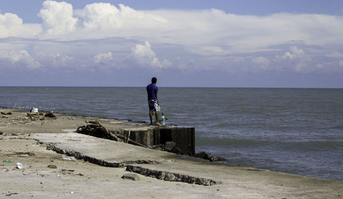 Man standing at beach against sky