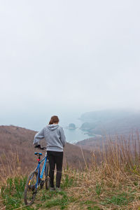 Rear view of woman standing with bicycle on mountain