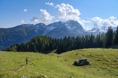 Rear view of woman walking on field against mountain range