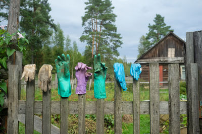 Clothes drying on wooden fence by trees against sky