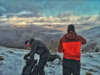 People on snow covered mountain against sky